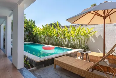 a swimming pool with a chair and an umbrella at Braban Sari Bali in Seminyak
