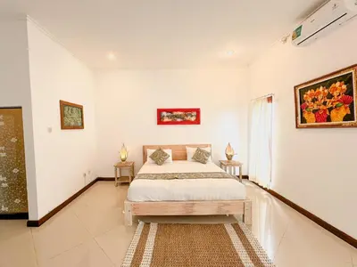a white bedroom with a bed and two tables at Bby Diamond Villa in Seminyak