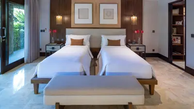 two beds in a room with two tables at Villa Asta in Seminyak
