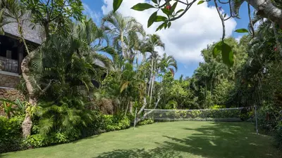 a lush green yard with trees and a fence at Villa Asta in Seminyak