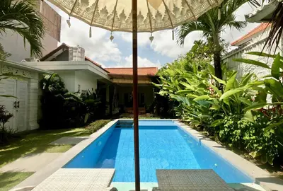 an umbrella over a swimming pool in front of a house at 3 neighbour villas 3 pools near Atlas Beach Club in Canggu