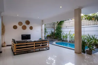 a living room with a couch and a swimming pool at Villa Yuhi in Seminyak
