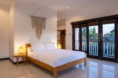 a bedroom with a bed and a balcony at Villa Yuhi in Seminyak