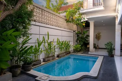 a swimming pool in a garden with plants at Villa Yuhi in Seminyak