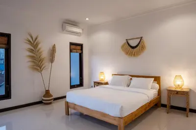 a bedroom with a bed and two lamps on two tables at Villa Yuhi in Seminyak