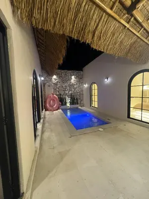 an indoor swimming pool in a building with a thatched ceiling at Antanaya Villa Seminyak in Seminyak