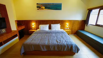 a bedroom with a bed and a couch and a television at BAGUS Guest House in Legian