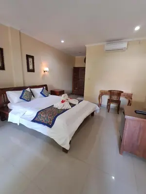 a bedroom with a large bed and a desk at SURFARIS INN on poppies 2 in Legian