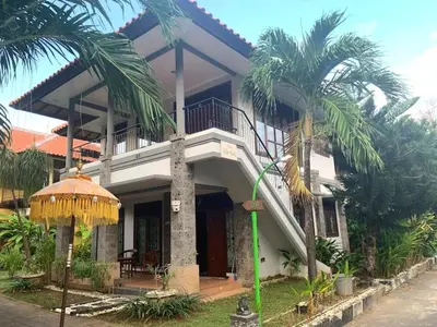 a large house with a balcony and palm trees at Villa D Lima Top Floor in Kuta