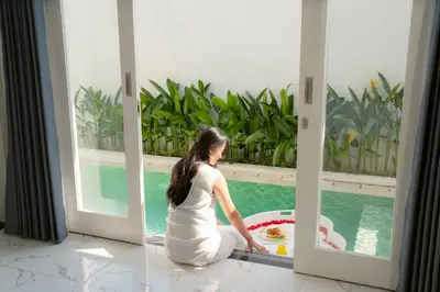 a woman sitting on the floor in front of a pool at Dikubu Bali Villa and Suites in Kerobokan