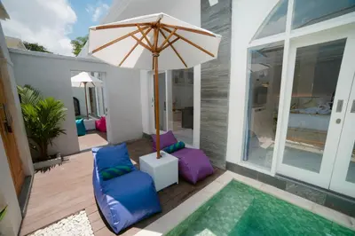 a patio with an umbrella and chairs and a pool at Dikubu Bali Villa and Suites in Kerobokan