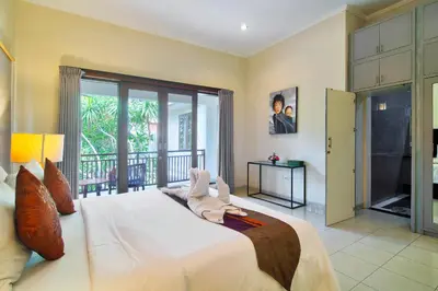 a bedroom with a large white bed with a balcony at Kefi Villa Seminyak in Seminyak