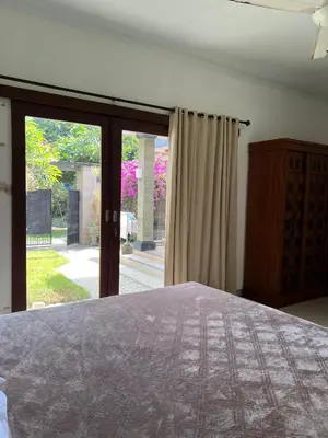 a bedroom with a bed and a sliding glass door at Pondok Ledog 01 in Badung