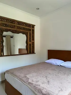 a bedroom with a bed and a large mirror at Pondok Ledog 01 in Badung