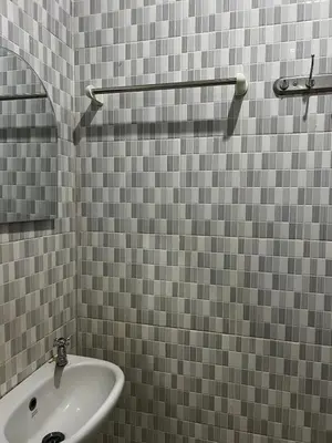 a bathroom with a white sink and gray tiled walls at Pondok Ledog 01 in Badung