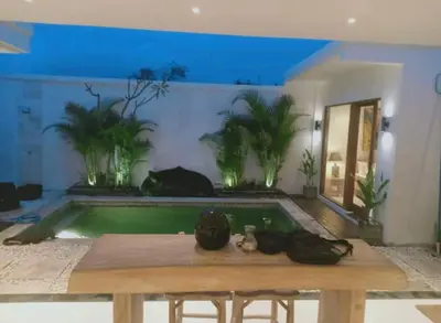 a pool with a table and a cat in a room at Villa umara 2 kerobokan close to seminyak in Seminyak