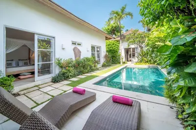 a villa with a swimming pool and two chairs at Villa Tara by Villa Finder in Seminyak