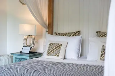 a bedroom with a bed with pillows and a table at Villa Tara by Villa Finder in Seminyak