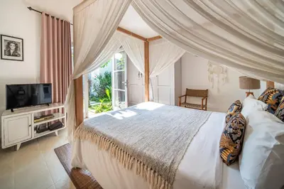 a bedroom with a large bed and a television at Villa Tara by Villa Finder in Seminyak