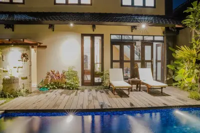 a villa with a swimming pool and two chairs at Shira House Bali in Legian