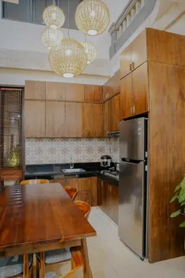 a kitchen with a table and a stainless steel refrigerator at Shira House Bali in Legian