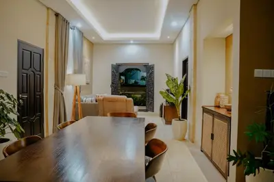 a living room with a wooden table and chairs at Shira House Bali in Legian