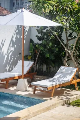 two lounge chairs and an umbrella next to a pool at Two Bedroom Villa with Outdoor Pool in Umalas