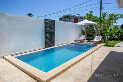 a swimming pool with two chairs and an umbrella at Two Bedroom Villa with Outdoor Pool in Umalas