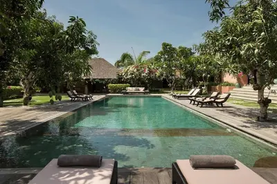 a swimming pool with chaise lounges in a resort at Villa MAMOUNE in Canggu