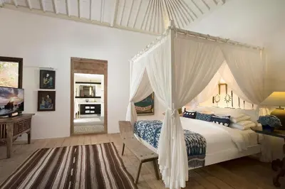 a bedroom with a canopy bed and a desk at Villa MAMOUNE in Canggu