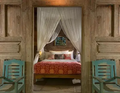 a bedroom with a bed with two blue chairs at Villa MAMOUNE in Canggu