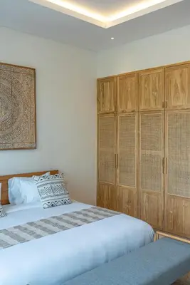a bedroom with two beds and wooden cabinets at Casa Kameelya - Modern Tropical 4BR Villa in Central Canggu in Canggu
