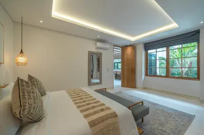 a bedroom with a large bed and a window at Casa Kameelya - Modern Tropical 4BR Villa in Central Canggu in Canggu