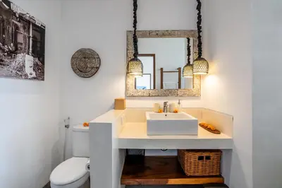 a bathroom with a white sink and a mirror at Athos Villa by iBali Management in Seminyak
