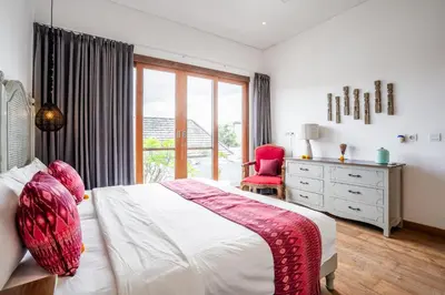 a bedroom with a bed and a dresser and a window at Athos Villa by iBali Management in Seminyak