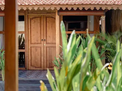 a wooden door in front of a house at Bale Bali Batubelig by ARM Hospitality in Canggu