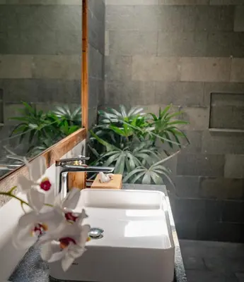 a white sink in a bathroom with plants at Bale Bali Batubelig by ARM Hospitality in Canggu