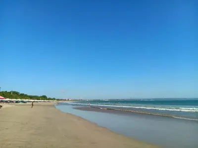 a beach with people on the sand and the ocean at Ellenbrook Rooms 17 by Mulia Cottage in Seminyak