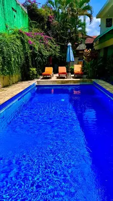 a swimming pool with two chairs and an umbrella at Ellenbrook Rooms 17 by Mulia Cottage in Seminyak