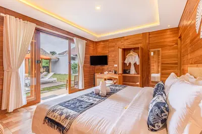 a bedroom with a large bed and a television at Anartha Resort Jimbaran By Kubu GWK in Jimbaran