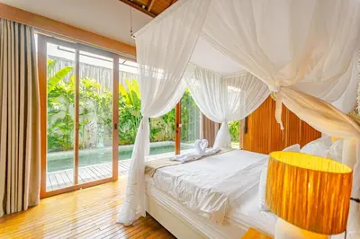 a bedroom with a white canopy bed and a window at Mya Harmony Villas Seminyak in Seminyak