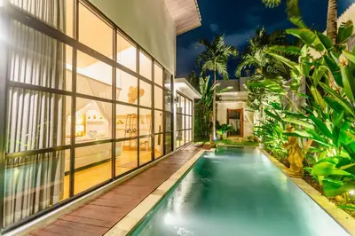 an indoor swimming pool in a house with windows at Mya Harmony Villas Seminyak in Seminyak