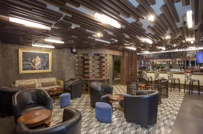 a lobby with chairs and tables and a bar at The Lerina Hotel Nusa Dua in Nusa Dua