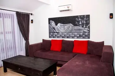 a living room with a brown couch with red pillows at Villa Gardenia - 6 Bedrooms with Pool in Seminyak in Seminyak