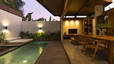 a swimming pool in a house with a dining area and a table at Rarama Teba Villa in Umalas