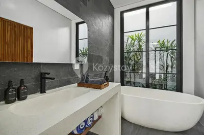 a bathroom with a large white tub and a window at Verde Villa by Kozystay - Umalas in Kerobokan