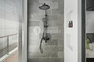 a shower in a bathroom with a stone wall at Verde Villa by Kozystay - Umalas in Kerobokan