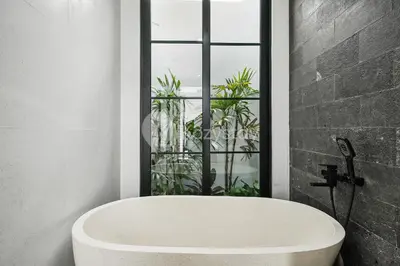 a white bath tub in a bathroom with a window at Verde Villa by Kozystay - Umalas in Kerobokan