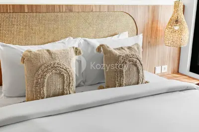 a bed with white pillows and a headboard at Verde Villa by Kozystay - Umalas in Kerobokan