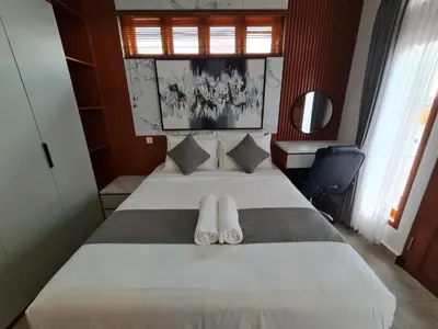 a bedroom with a bed with slippers on it at Shin In Bali in Kuta